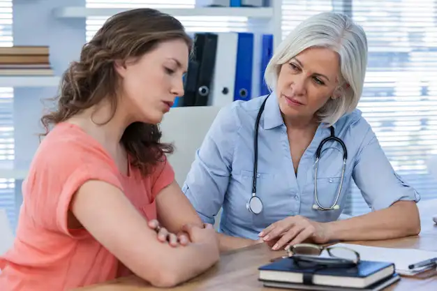 Female doctor consulting and comforting young woman during medical appointment