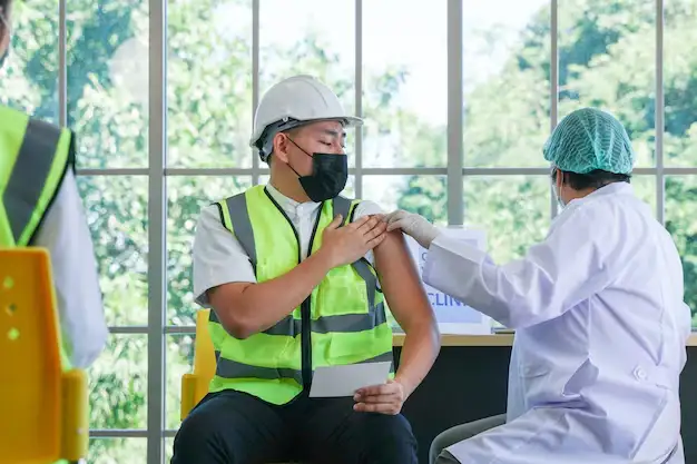Worker receiving vaccine from nurse.